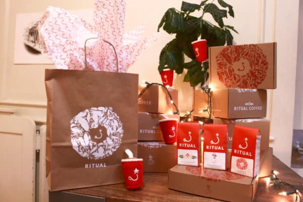 Cardboard boxes with red and white wreaths stacked into two columns decorated with string lights