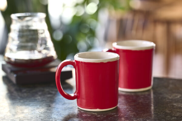 Two red ceramic mugs on a dark marble table