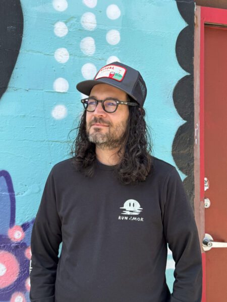 Person wearing a dark trucker hat with a designed embroidered patch.